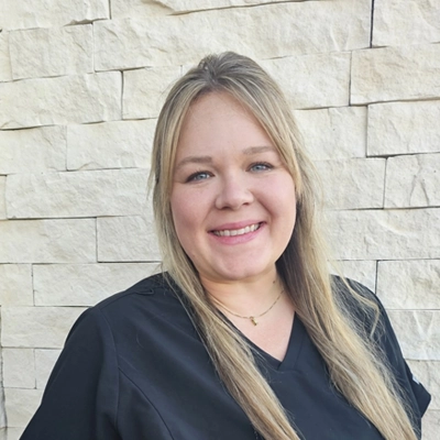 Natalie DeMasters smiling in front of a stone wall.