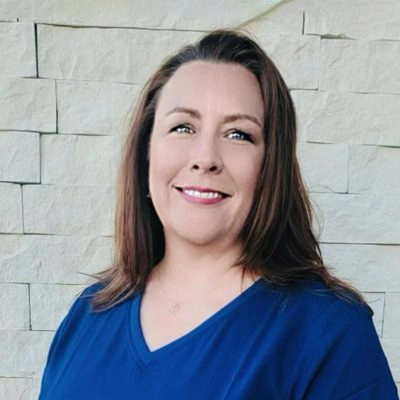 Marci Schwartz smiling in front of a stone wall.
