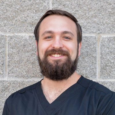 Dillan Friedrichs smiling in front of a stone wall.
