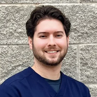 Jake Diamond smiling in front of a stone wall.