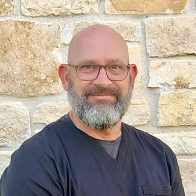 James S. Lorenz smiling in front of a stone wall.