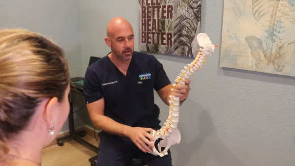 Matthew George giving a consultation. He is hold a spine.