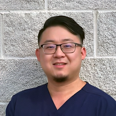 Michael Si smiling in front of a stone wall.