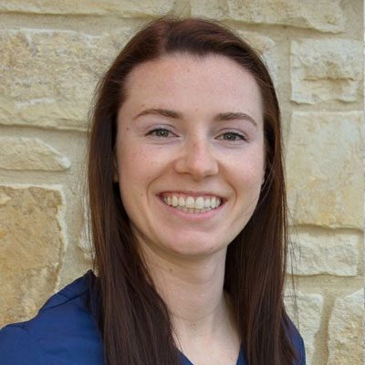 Nichole Roedel smiling in front of a stone wall.