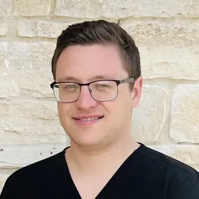 Logan Hengst smiling in front of a stone wall.