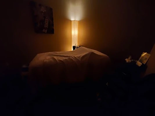 A dark lit room with a massage table in the center.