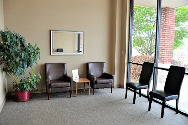 A waiting room with chairs and a plant.