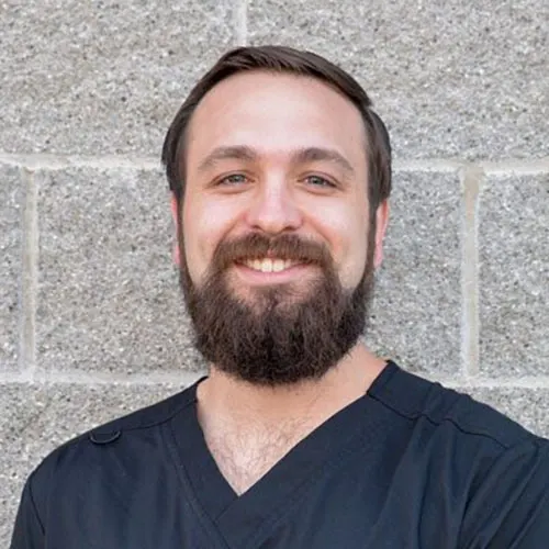 Dillan Friedrichs smiling in front of a stone wall.