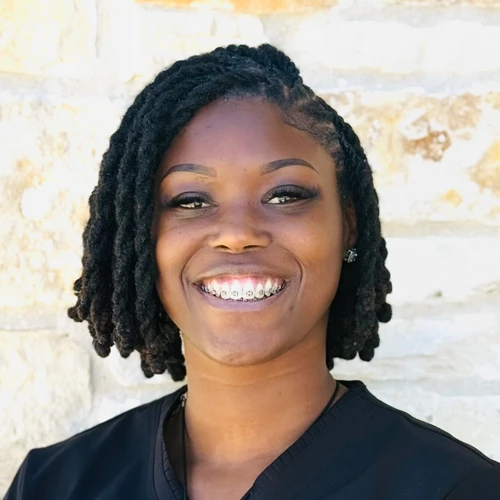 Shaquita Kelly smiling in front of a stone wall.