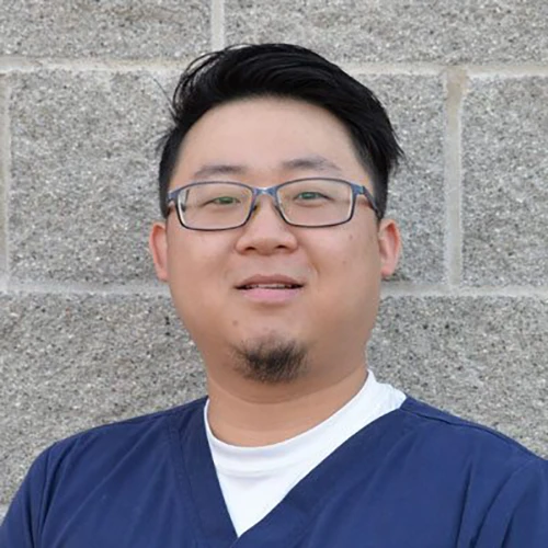 Michael Si smiling in front of a stone wall.
