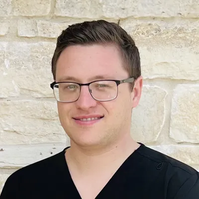 Logan Hengst smiling in front of a stone wall.