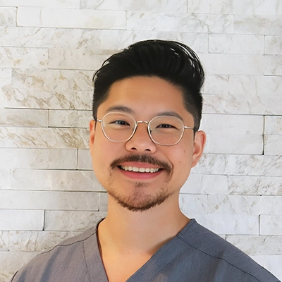 Matthew Kuo smiling in front of a brick wall.